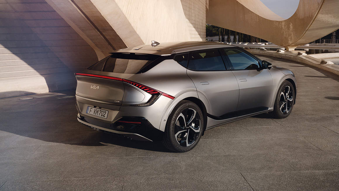 Kia EV6 from the side and back infront of some modern architecture